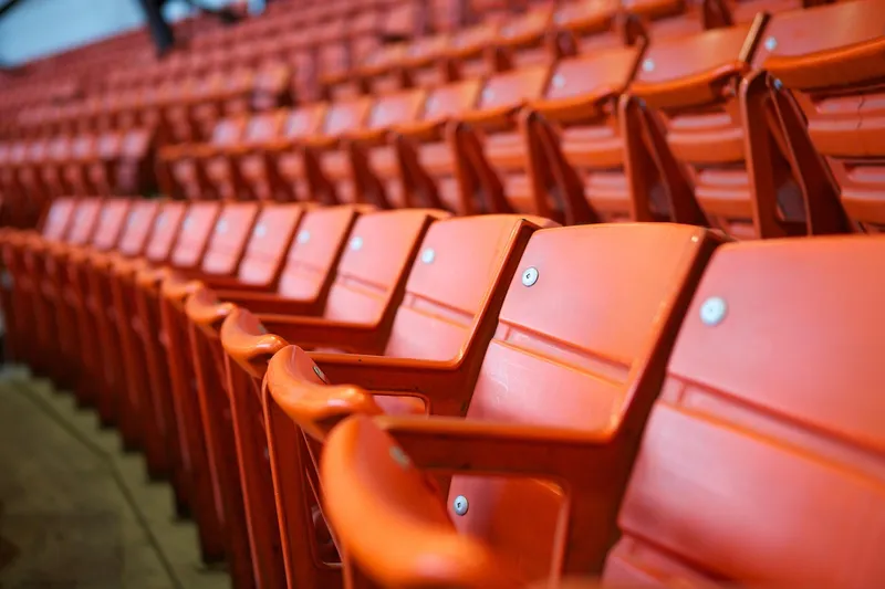 Fileiras de cadeiras vazias na arquibancada de um estádio