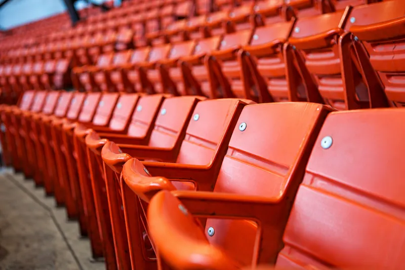 Fileiras de cadeiras vazias na arquibancada de um estádio