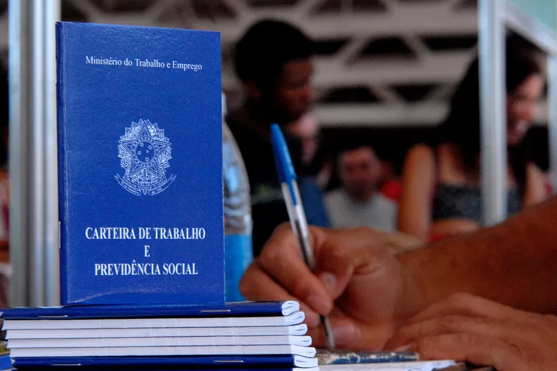 Carteiras de Trabalho empilhadas sobre uma mesa de atendimento